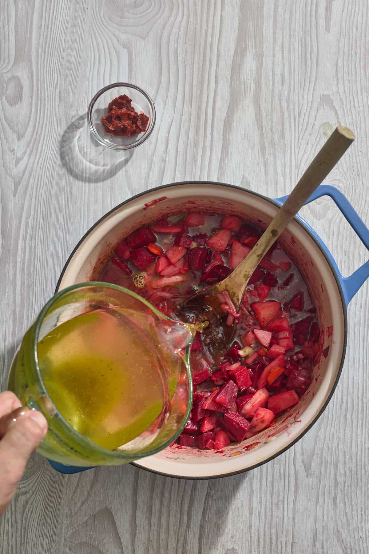 broth being poured into pot of vegetables