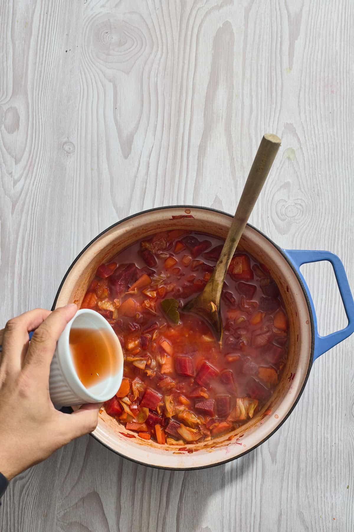 vinegar being poured into a pot of soup