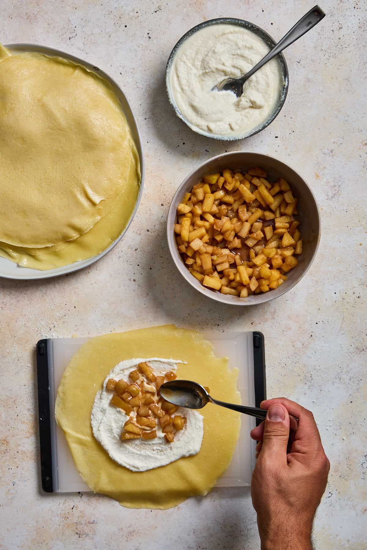 ricotta and apples being spread on a crepe