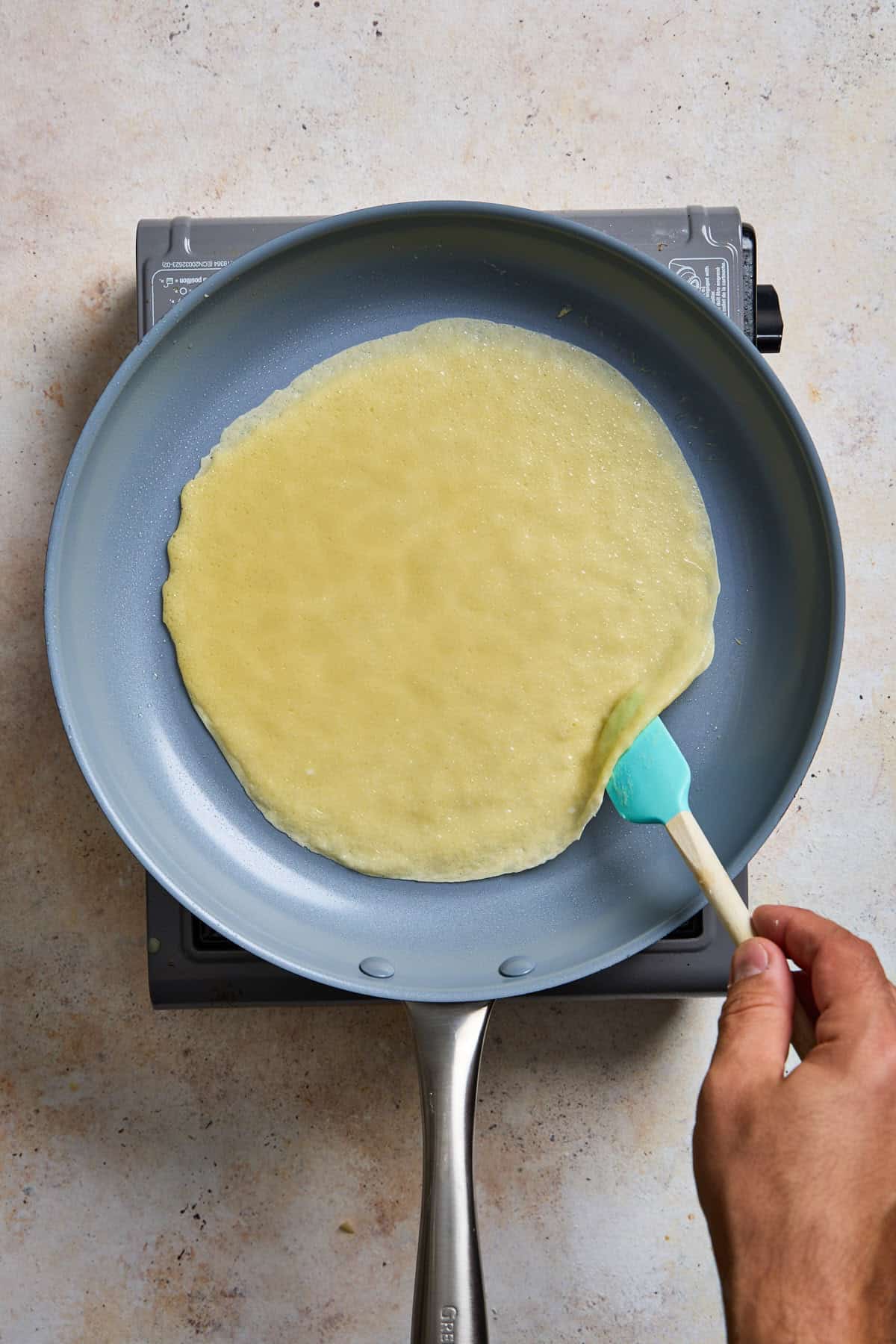 a crepe cooking in a nonstick skillet