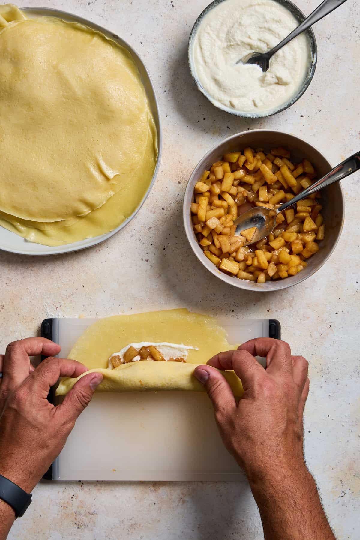 a crepe with filling being rolled on a cutting board