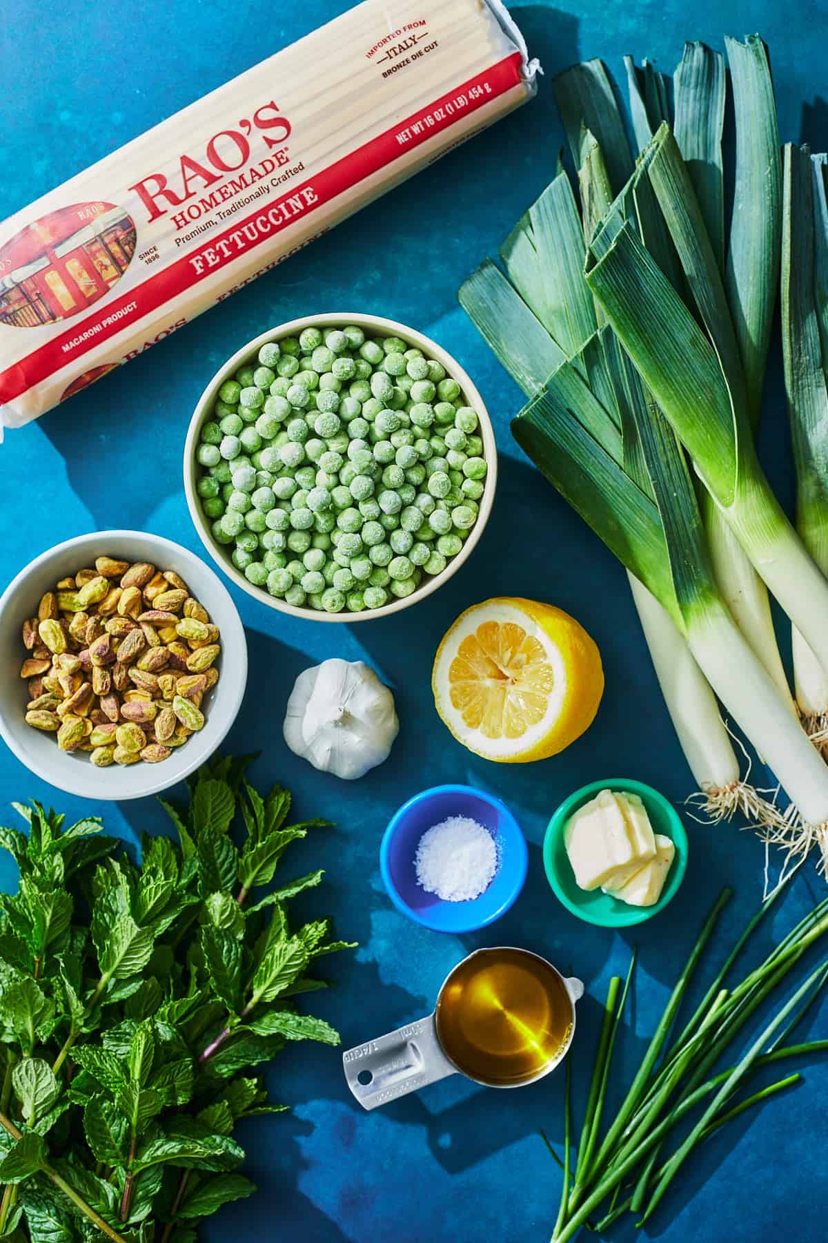 ingredients for green pea pasta with mint pistachio pesto on blue background