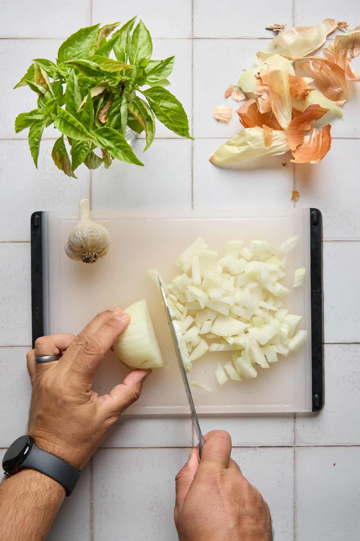 onion and garlic being chopped on a cutting board