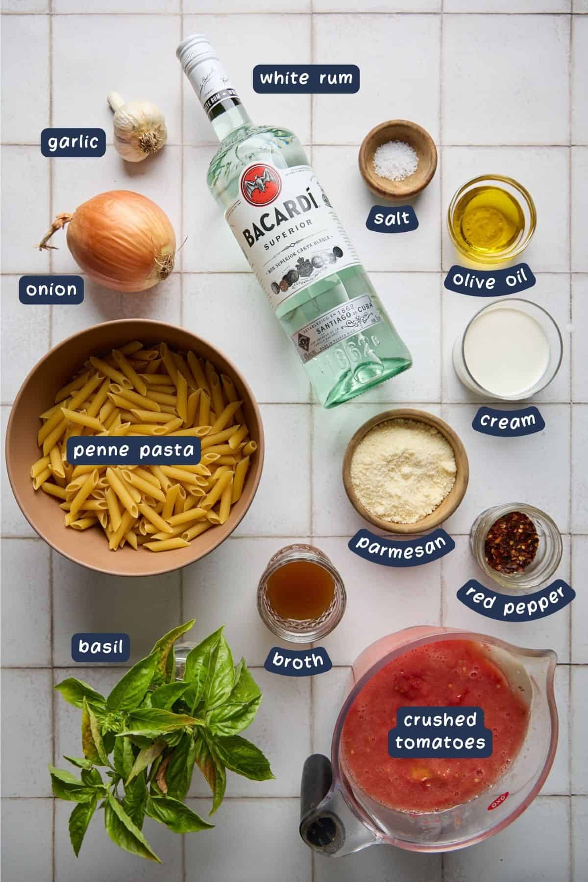 ingredients for making the rum pasta recipe on a white tiled background