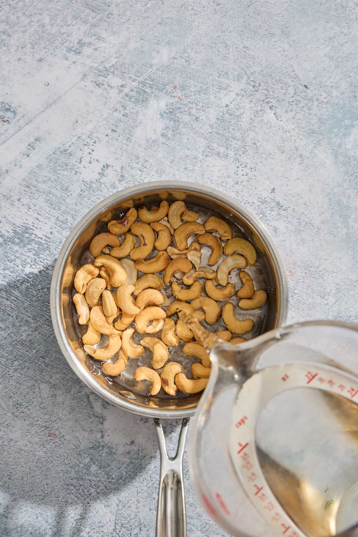 cashews in a pan with water being poured over them