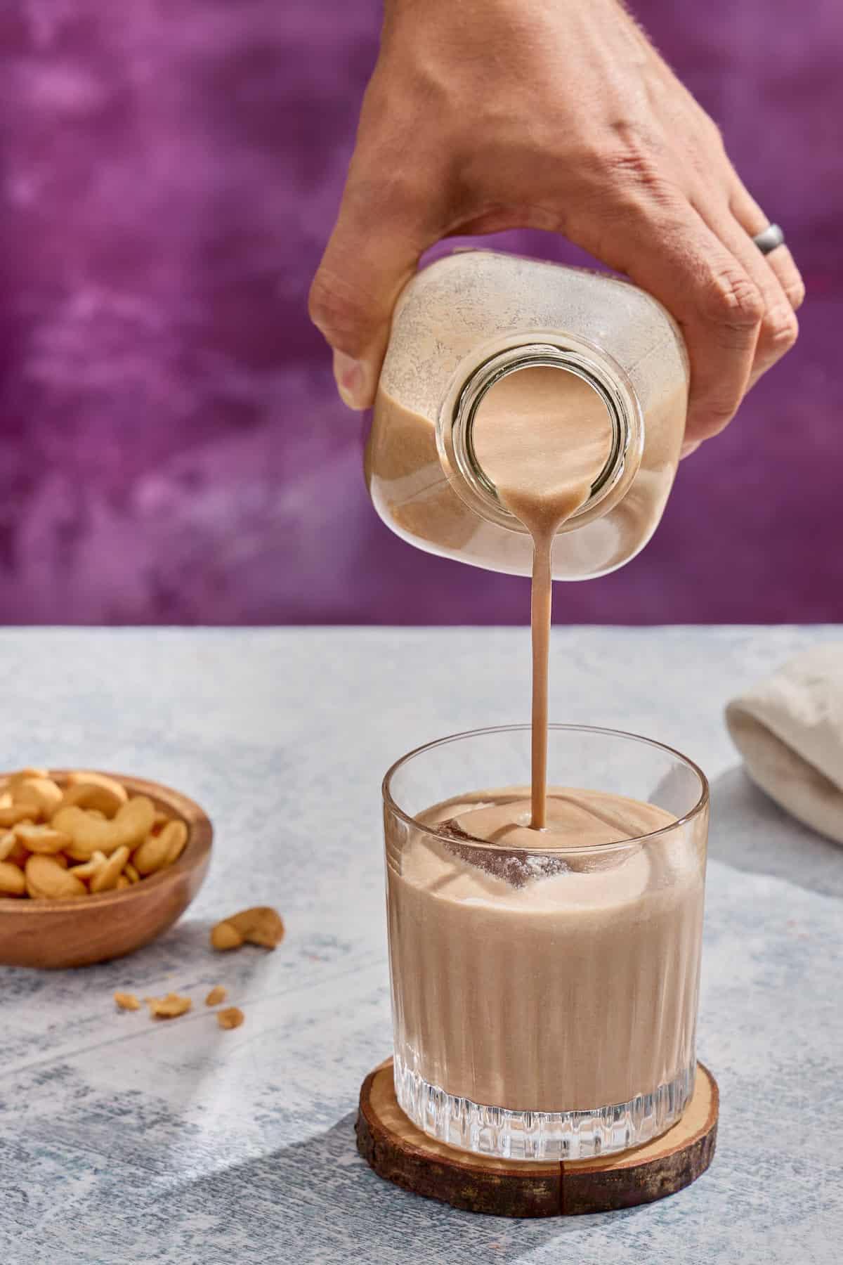 homemade irish cream being poured into a glass with ice