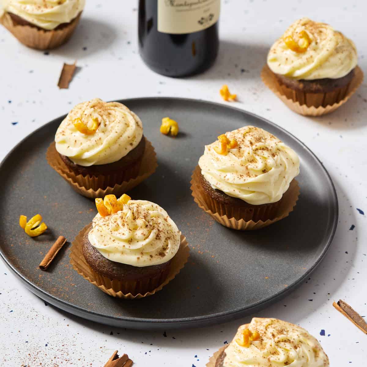 plate of cupcakes with orange zest, cinnamon, and bottle of wine