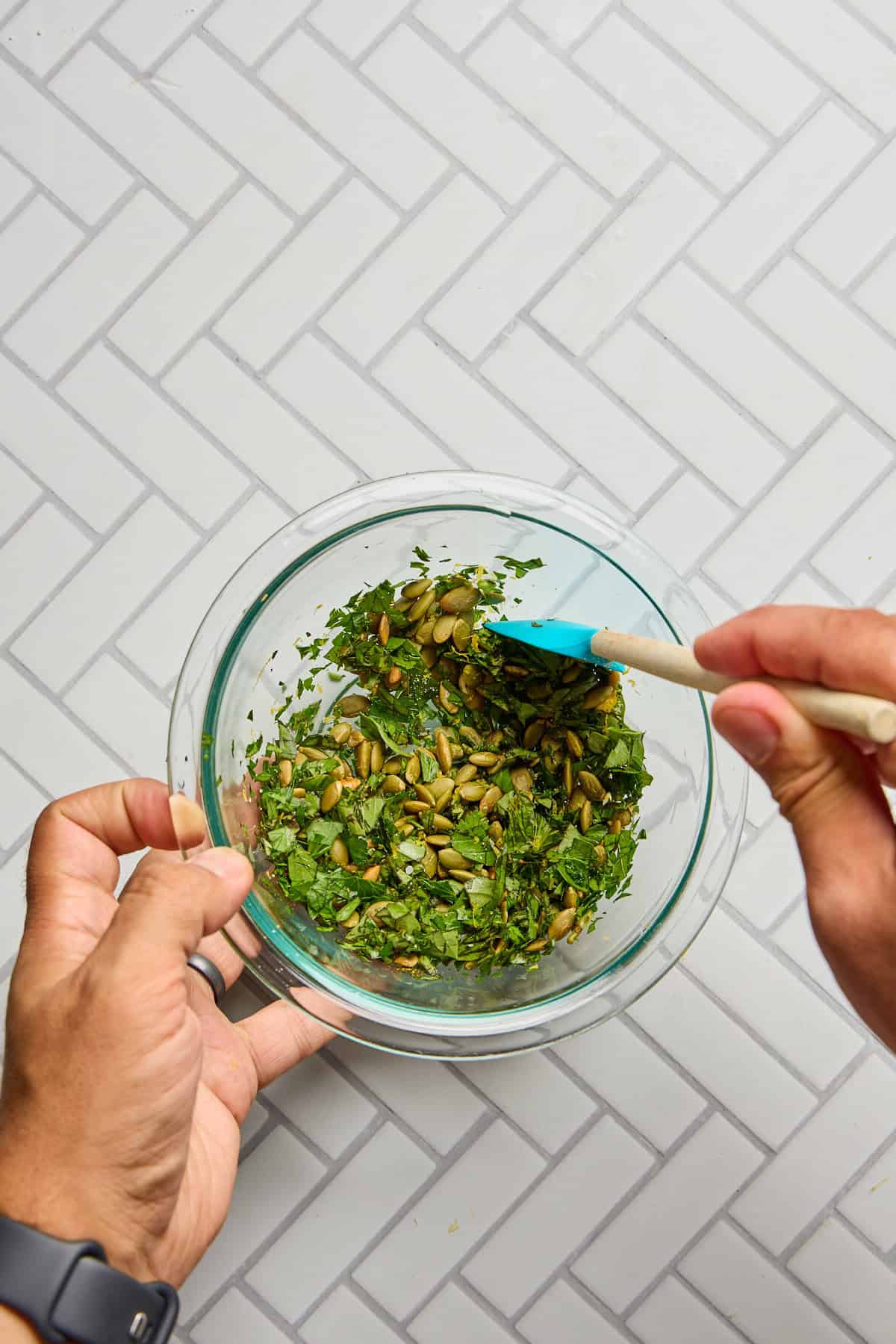 herbs and pepitas being mixed in a bowl