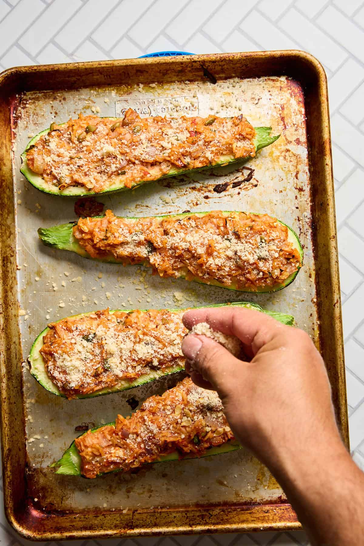 stuffed zucchini being sprinkled with parmesan cheese
