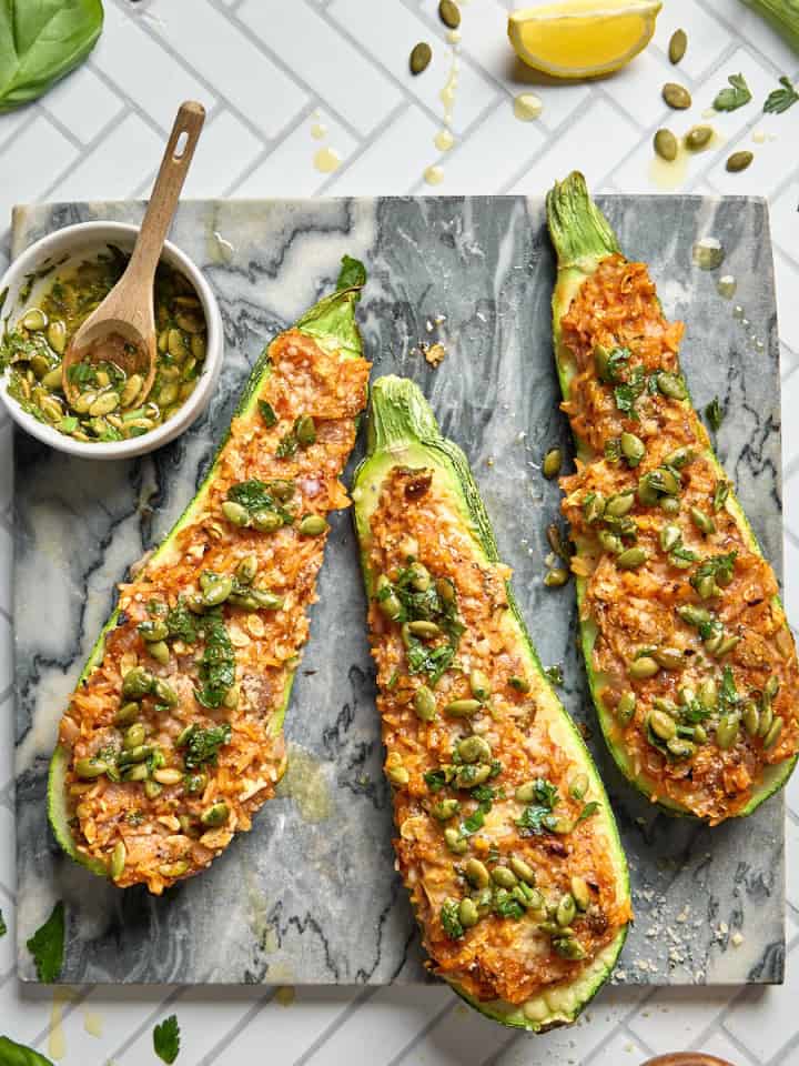 three stuffed zucchini halves on a cutting board