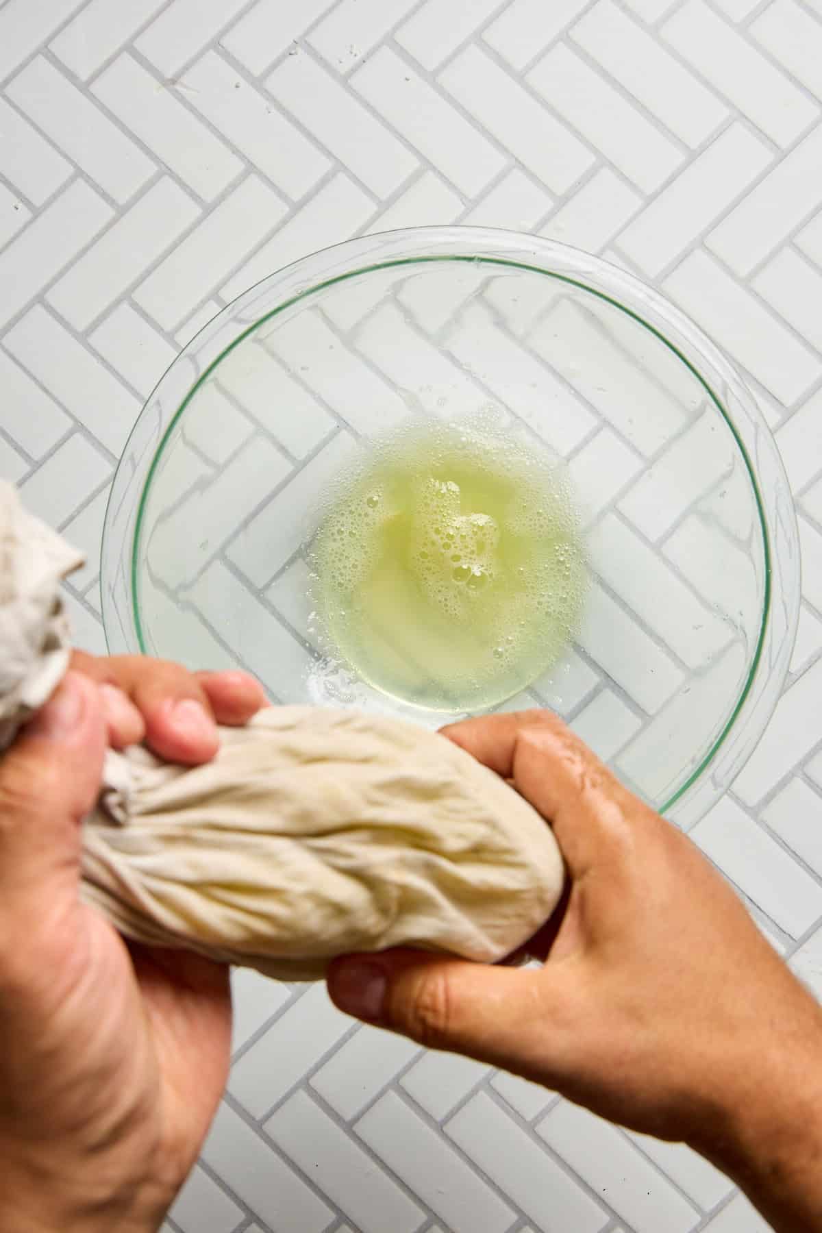 zucchini flesh being squeezed over a bowl of liquid