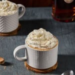 mugs and a bottle of rum with whipped cream