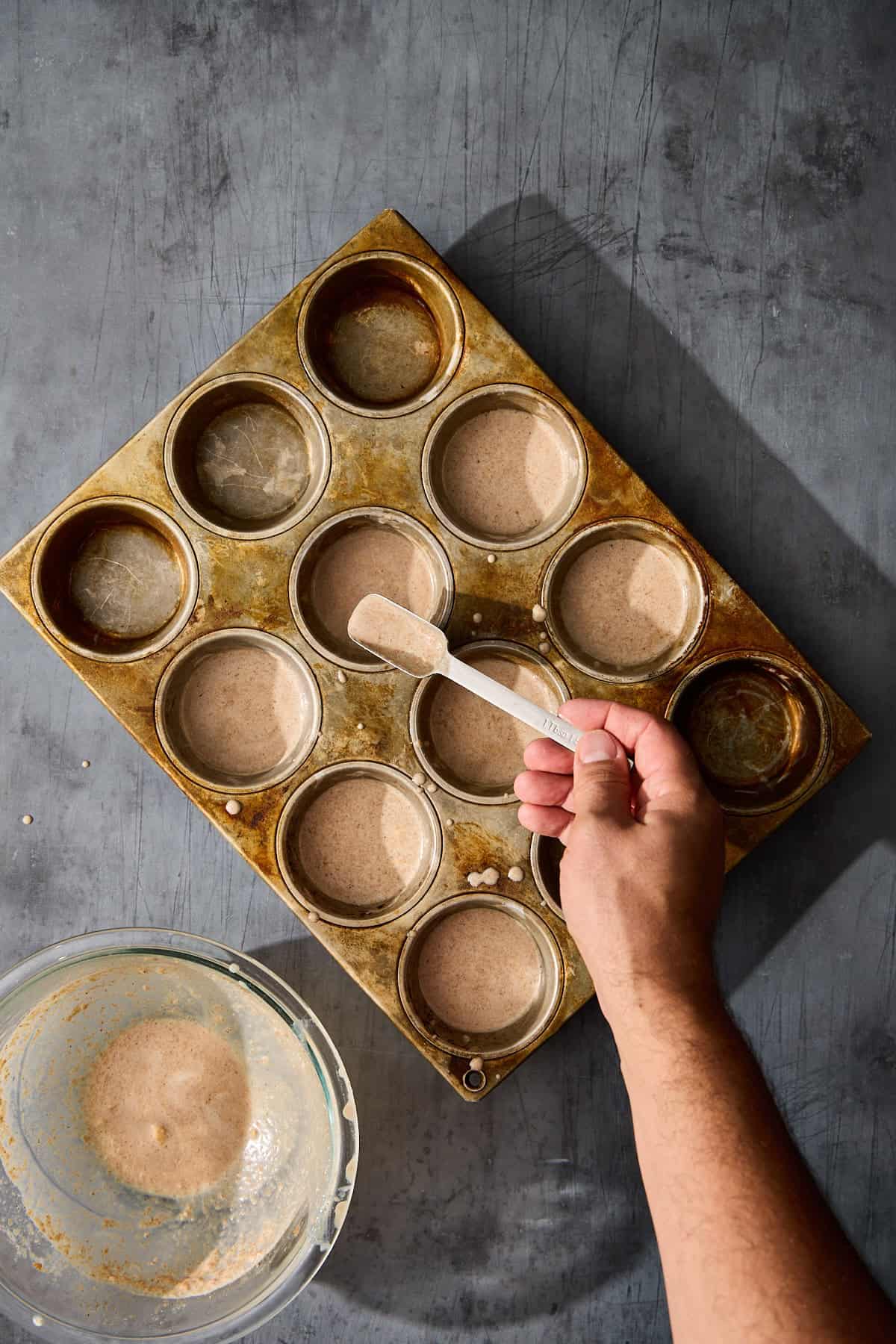 hot buttered rum batter being scooped into a mufifn tin