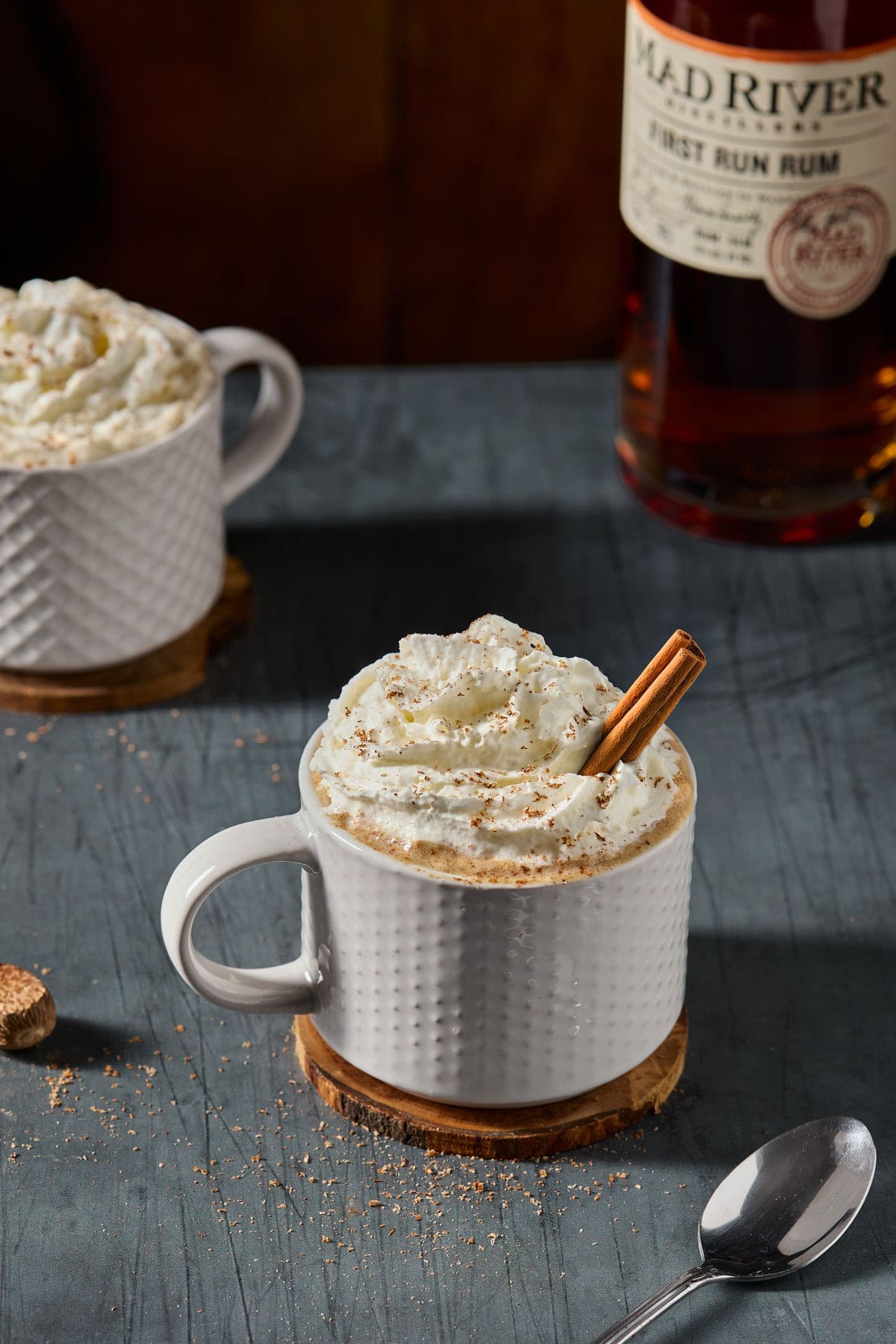 mugs of hot buttered rum with whipped cream and cinnamon sticks