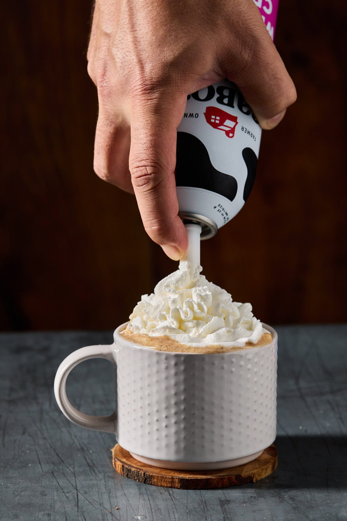 whipped cream being sprayed onto a drink in a mug