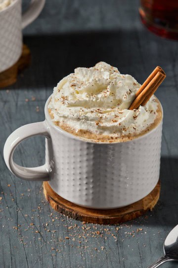 a mug of hot buttered rum with a cinnamon stick