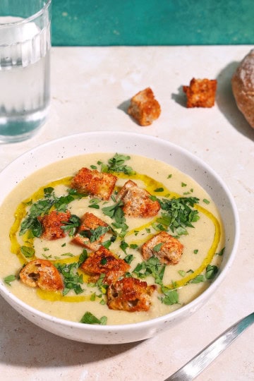 a bowl of soup with celery and leeks, and potatoes