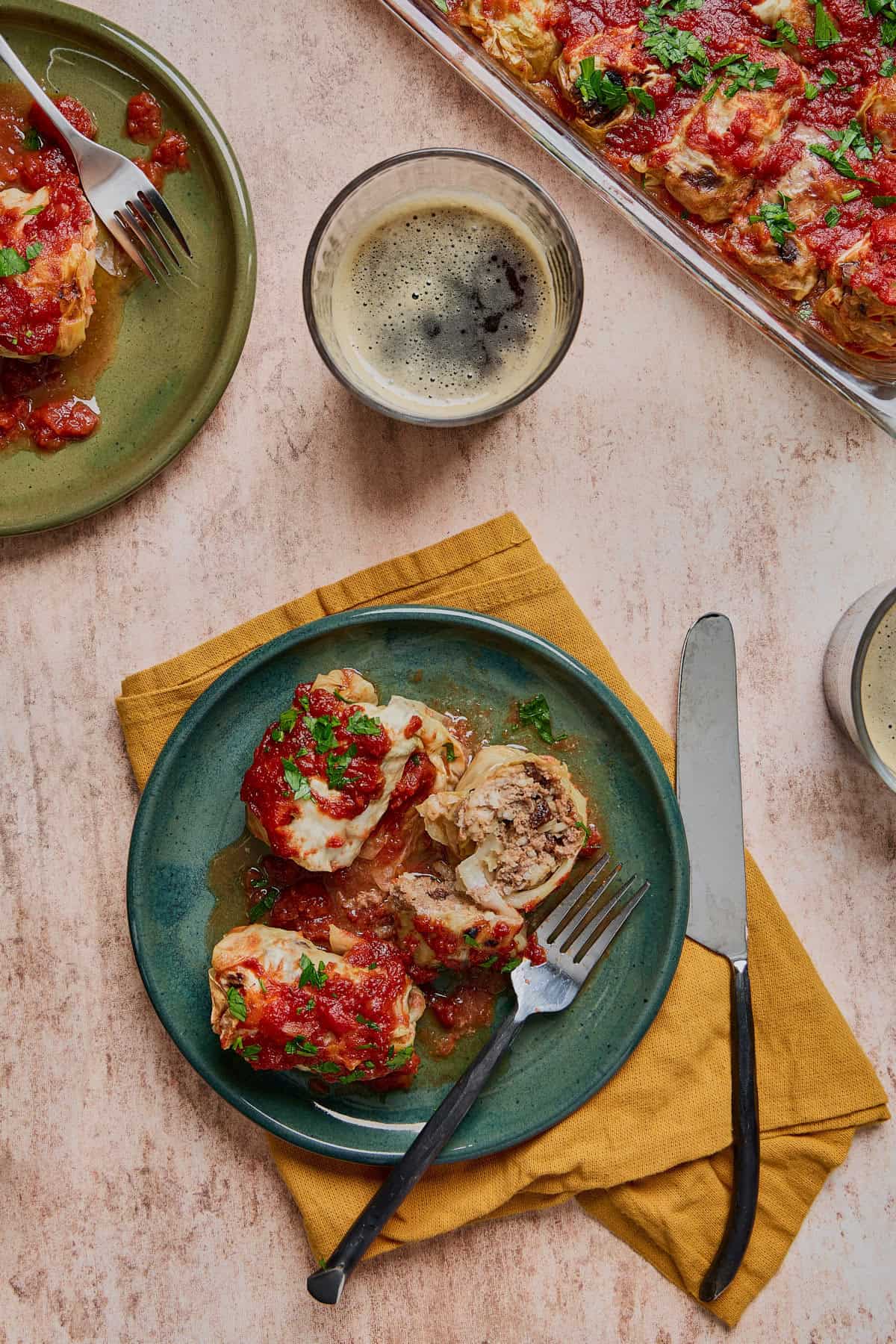 a plate of cabbage rolls sliced open with tomato sauce and a glass of beer