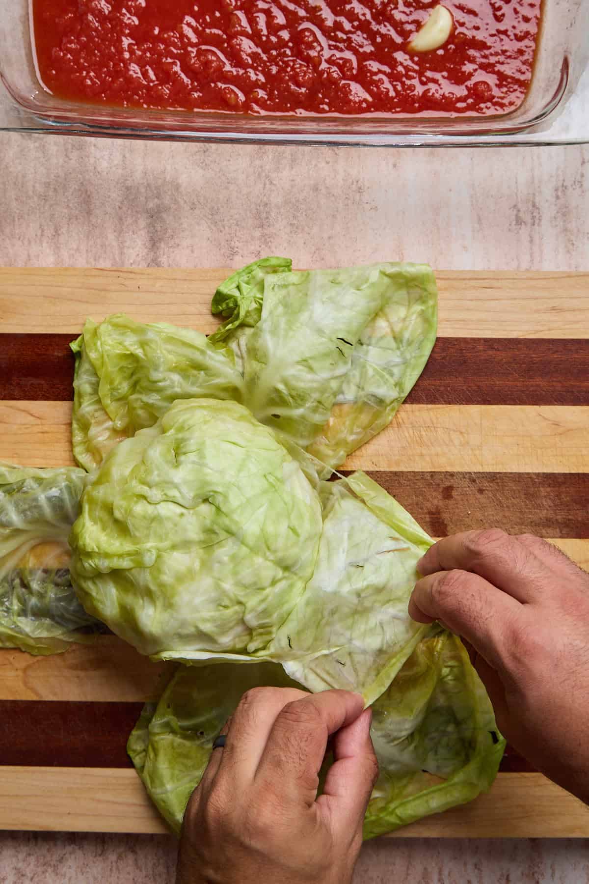leaves from a head of steamed cabbage being pulled apart