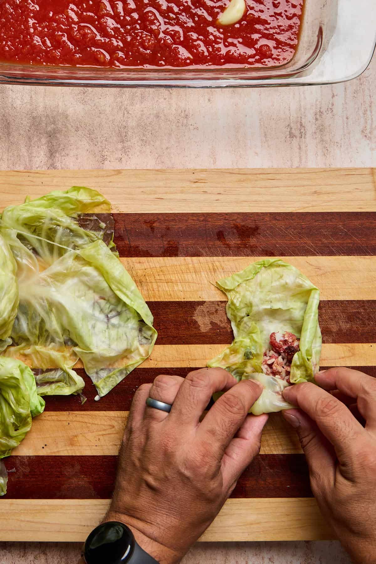a stuffed cabbage leaf being rolled up on a cutting board