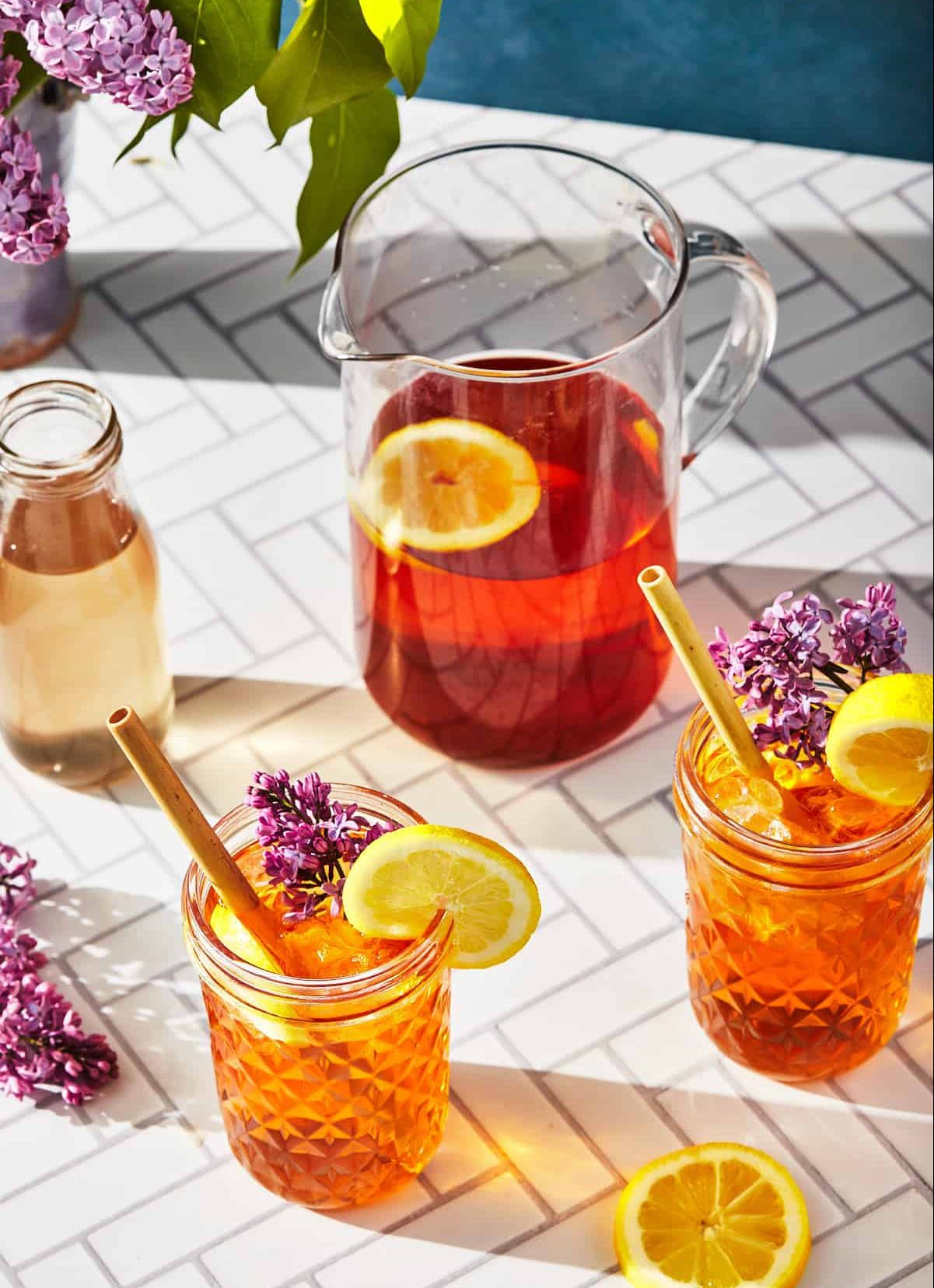glasses of lilac tea with a pitcher of tea and the lilac simple syrup