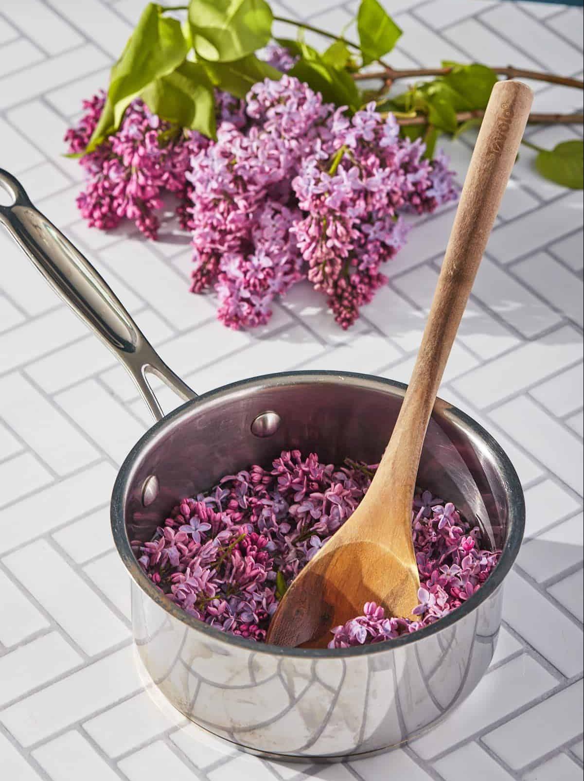 lilac flowers in a small pot with a spoon