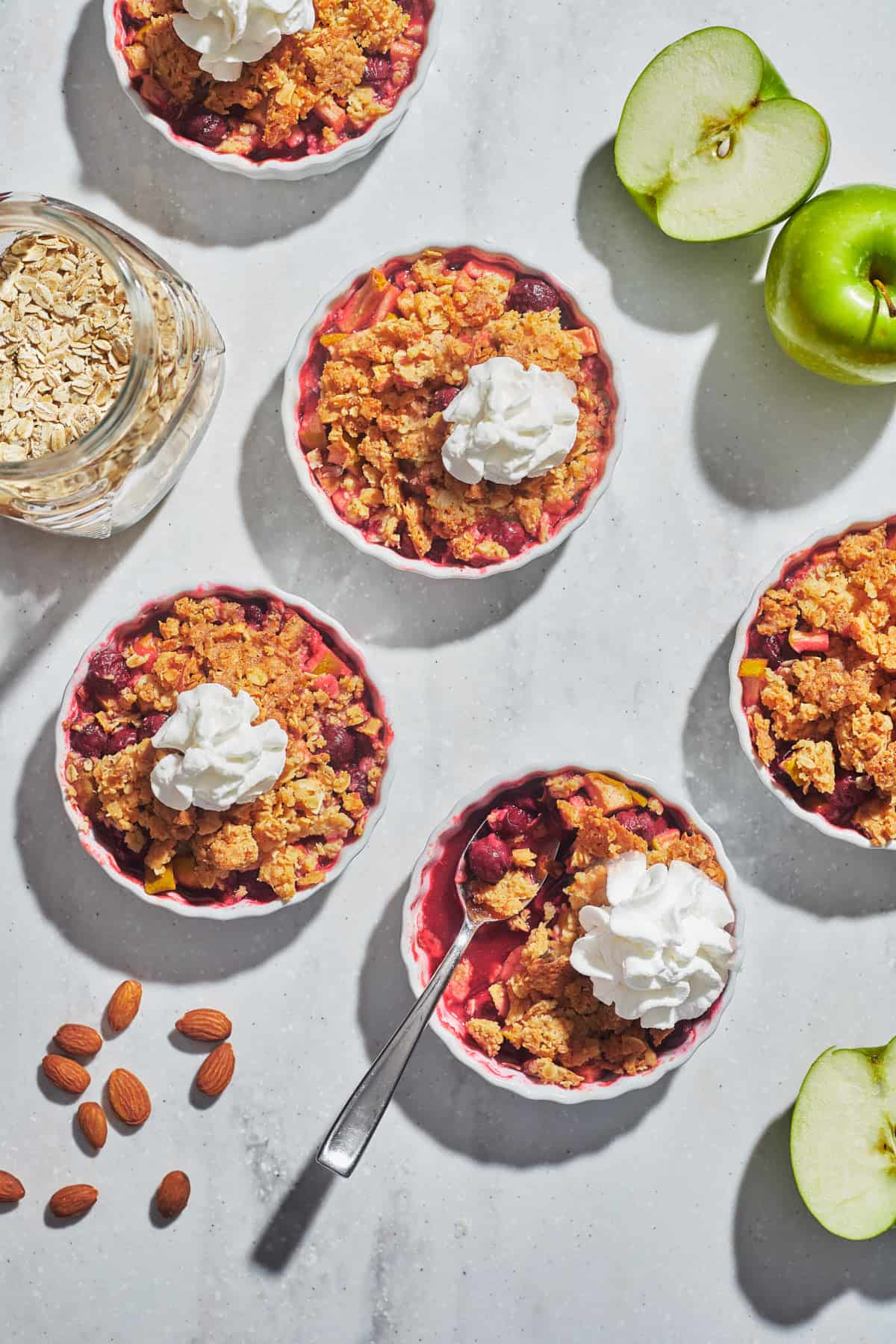 five small dishes of cherry crisp with whipped cream and apples 