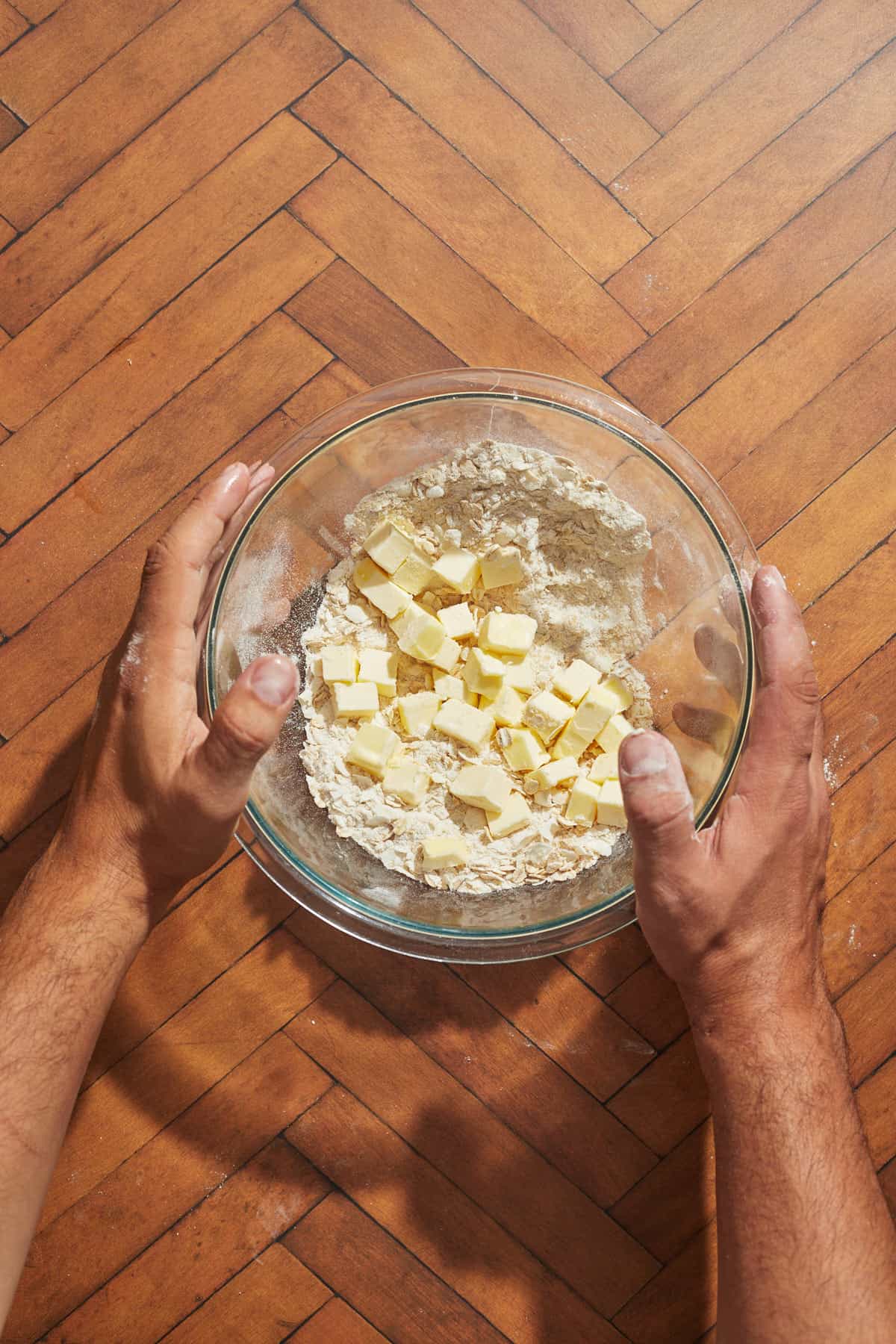 cubed butter pieces being added to the bowl of dry ingredients