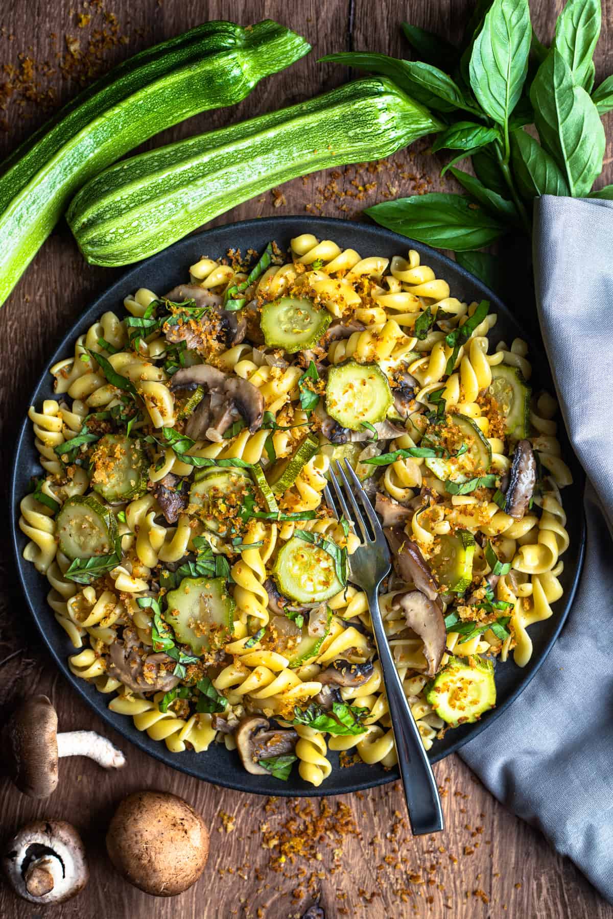 plate of zucchini and mushroom pasta with fork and napkin