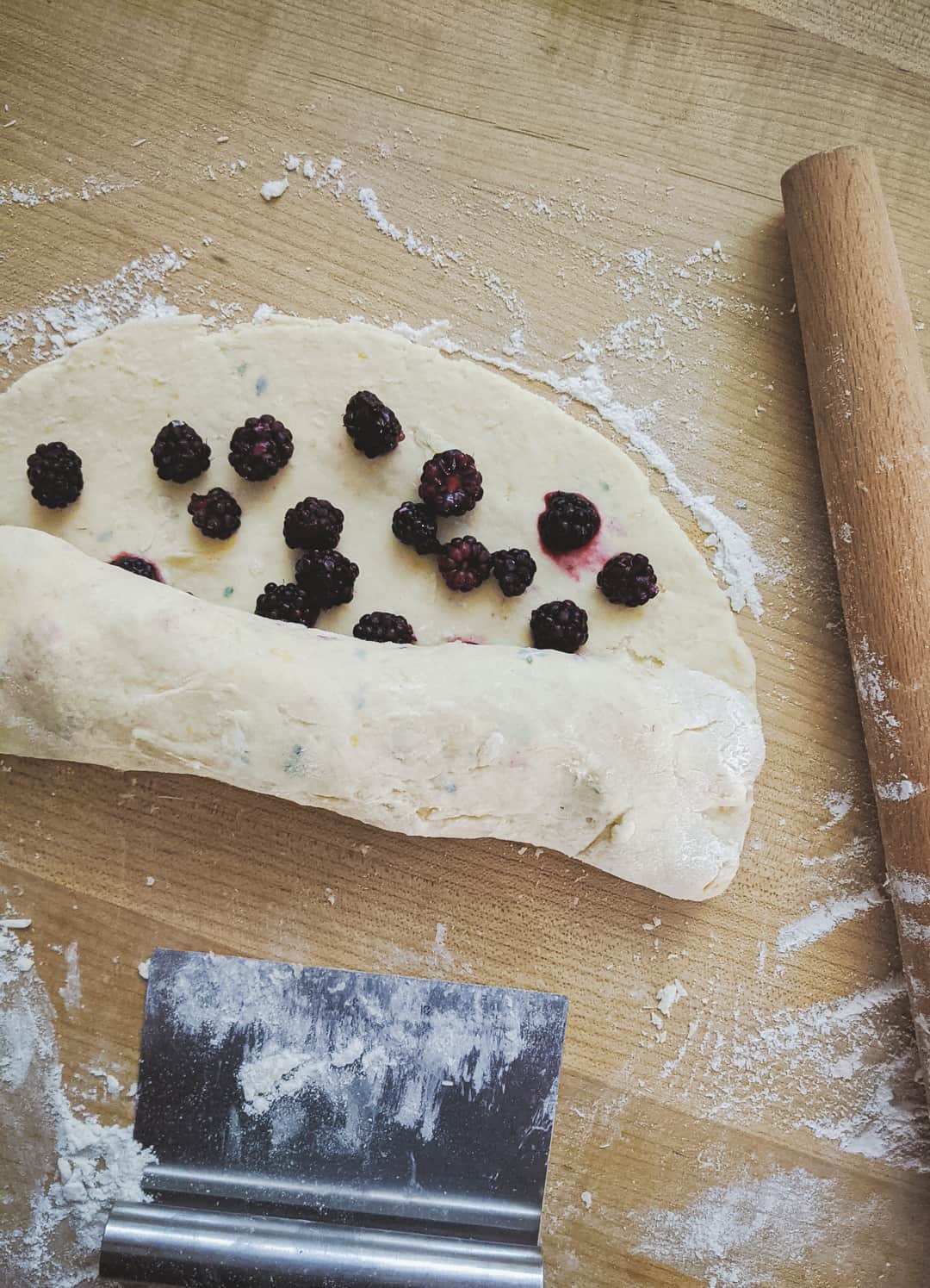 blackberries being rolled up into scone dough