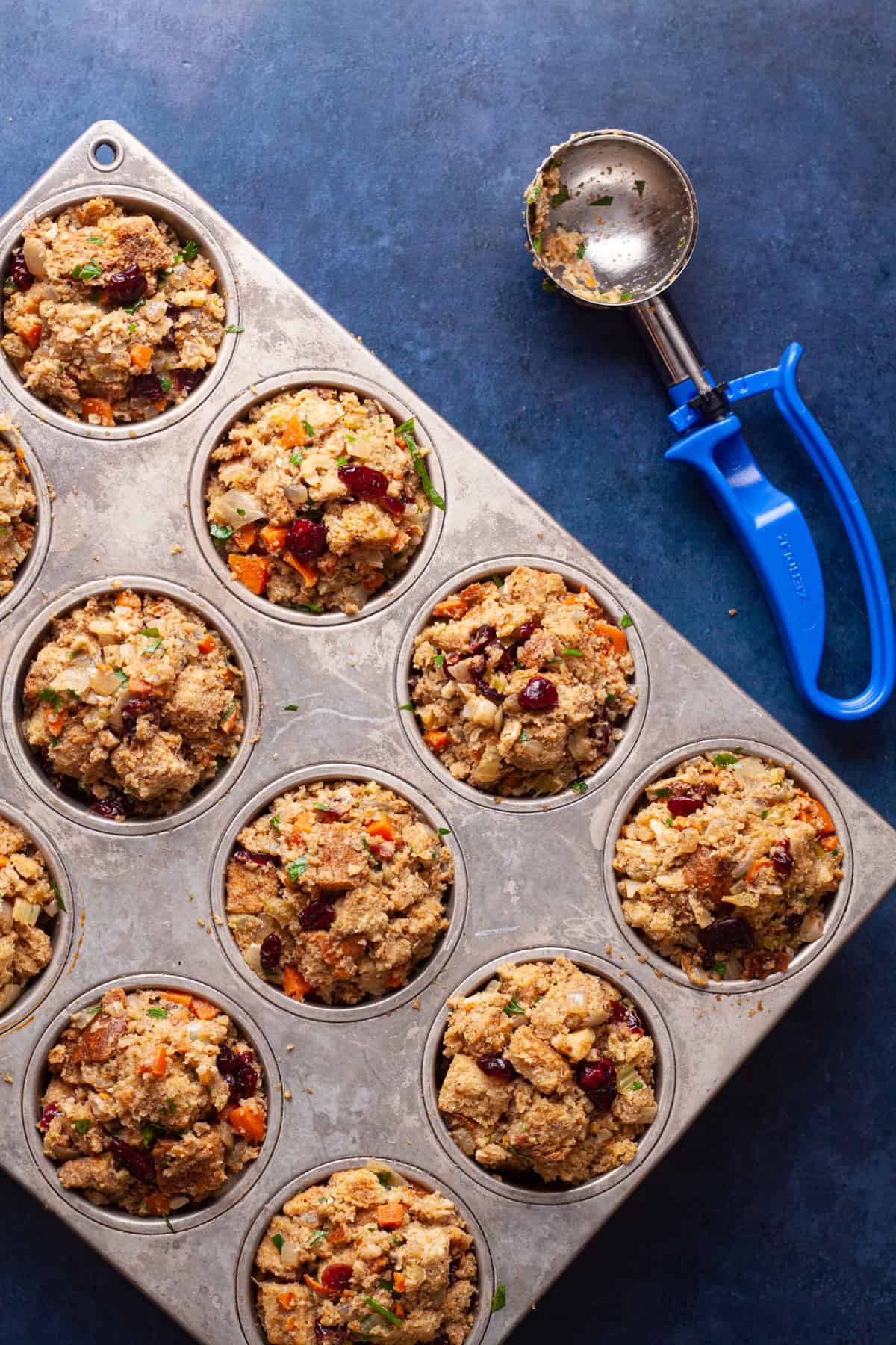 diving the walnut and cranberry stuffing into a muffin tin for baking