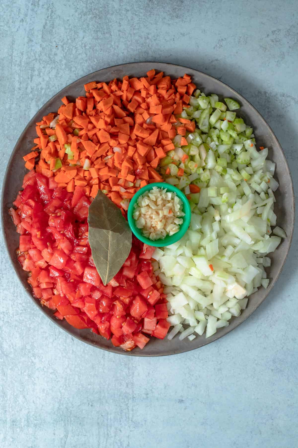 a plate of chopped carrots, onions, garlic and tomatoes