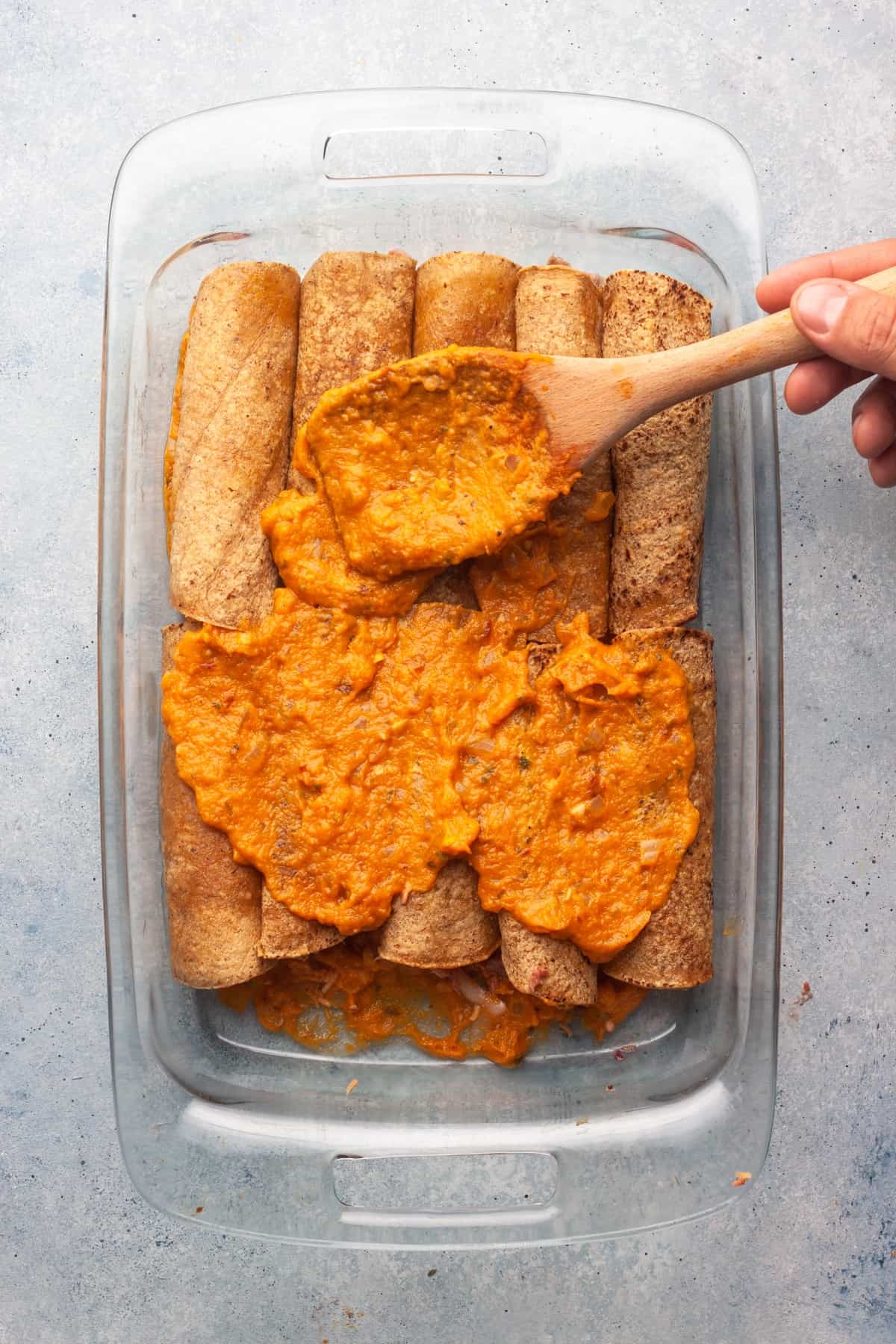 enchiladas with pumpkin sauce being spread over top