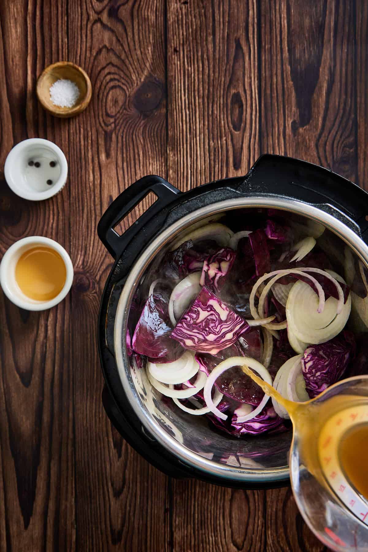 onions, cabbage, and broth being added to instant pot