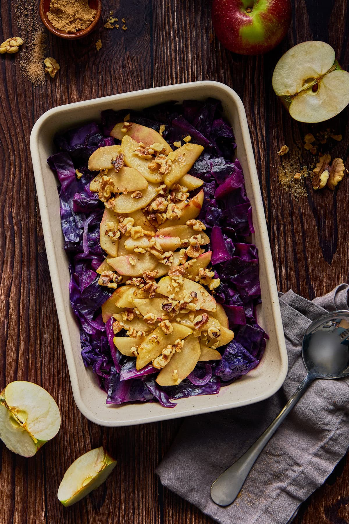 a serving dish filled with cooked red cabbage, apples, and walnuts