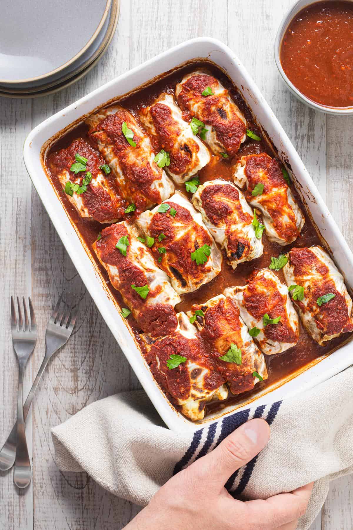 cooked cabbage rolls and sauce in a baking dish
