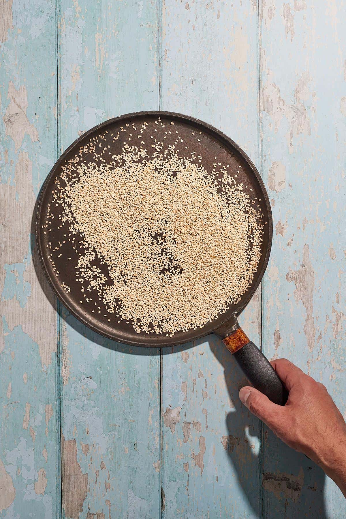 sesame seeds being toasted in a pan