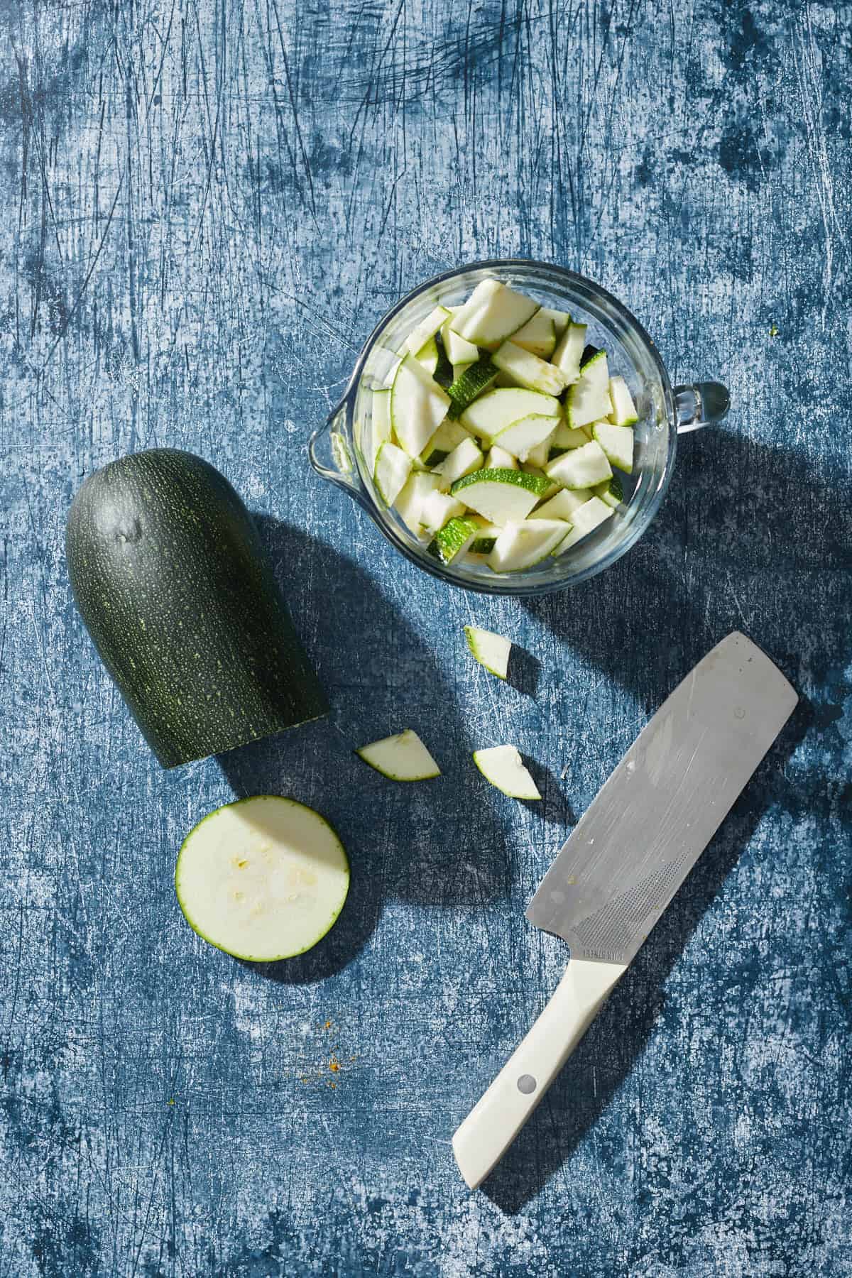 a large zucchini with chopped up pieces and a chef's knife
