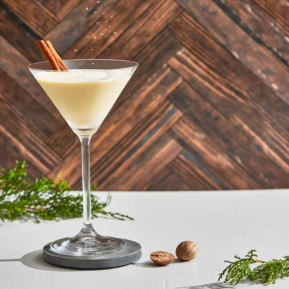 a glass of eggnog cocktail with a cinnamon stick