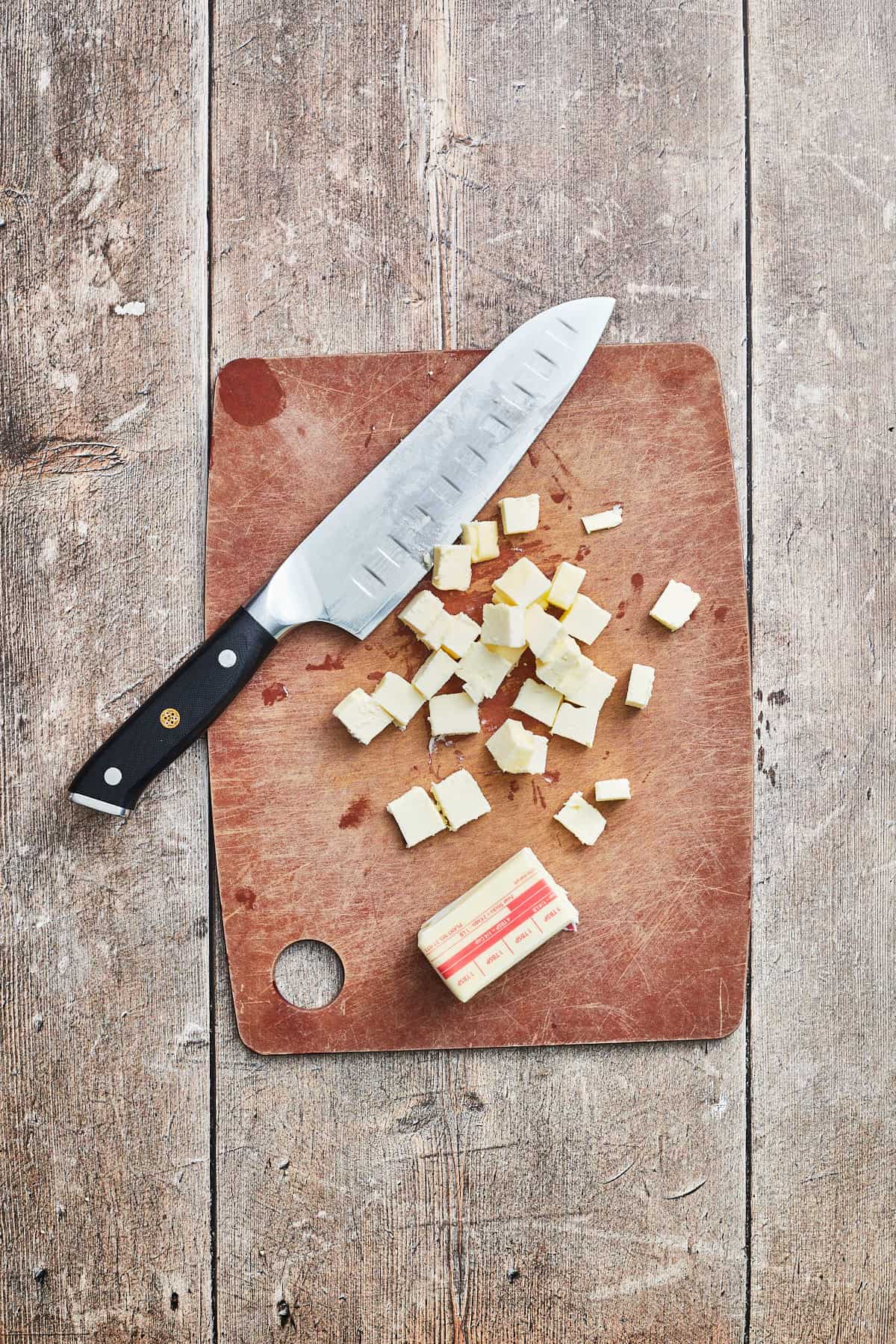 butter on a small cutting board with a knife cut into small cubes
