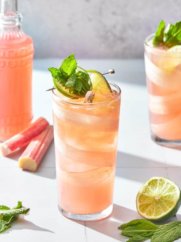 glasses of rhubarb gin cocktail with a bottle of rhubarb juice