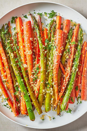 a plate of carrots and asparagus roasted and topped with breadcrumbs
