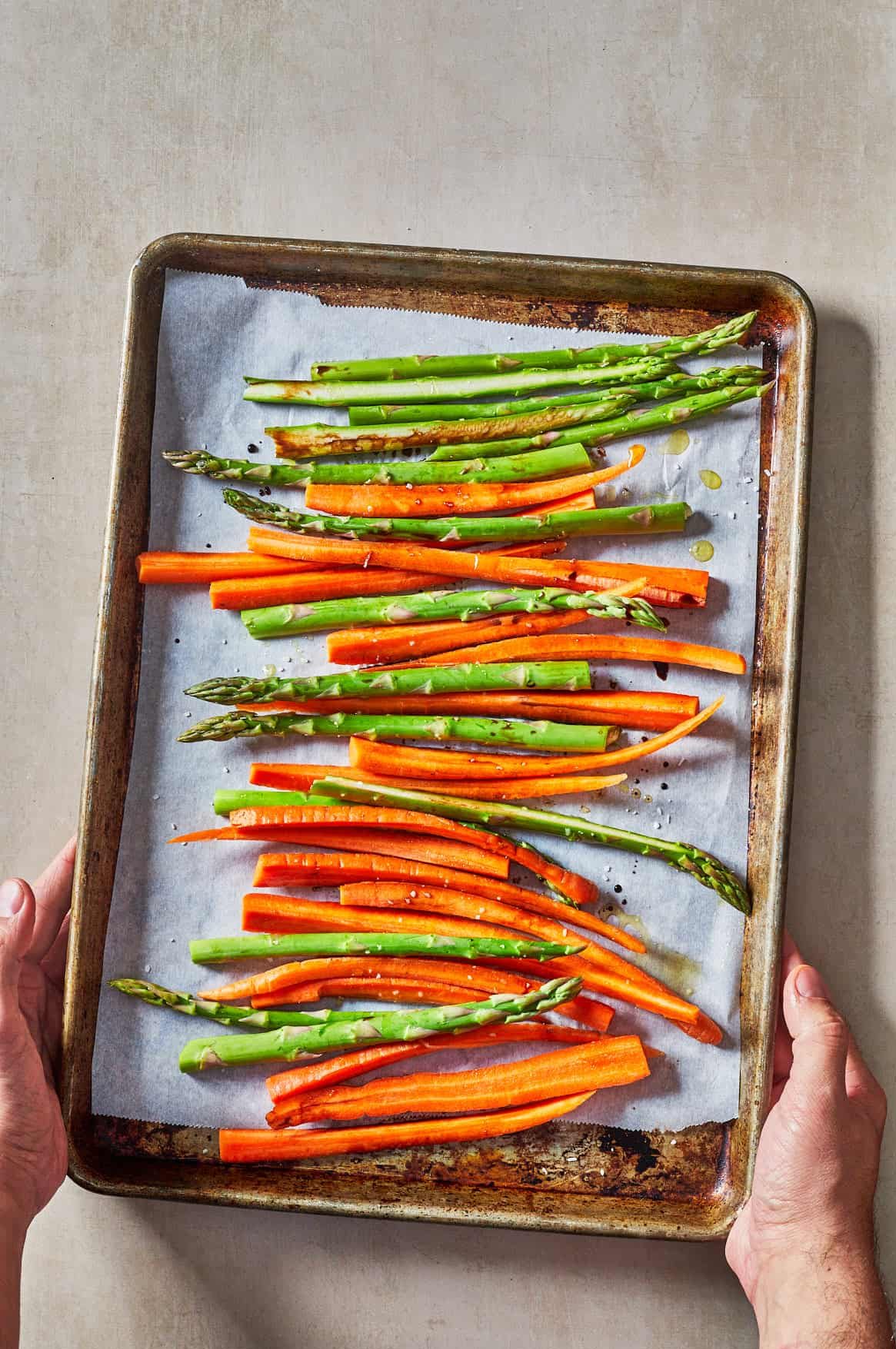 asparagus and carrots on a baking sheet lined with parchment