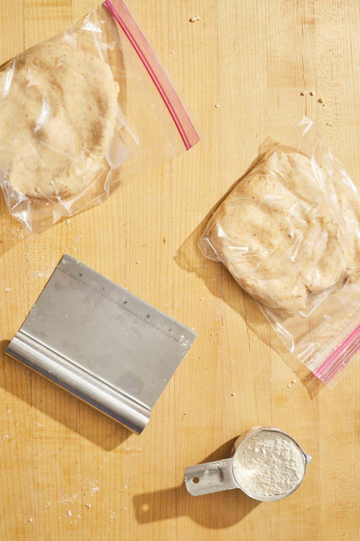pie dough divided into two plastic bags on counter with flour