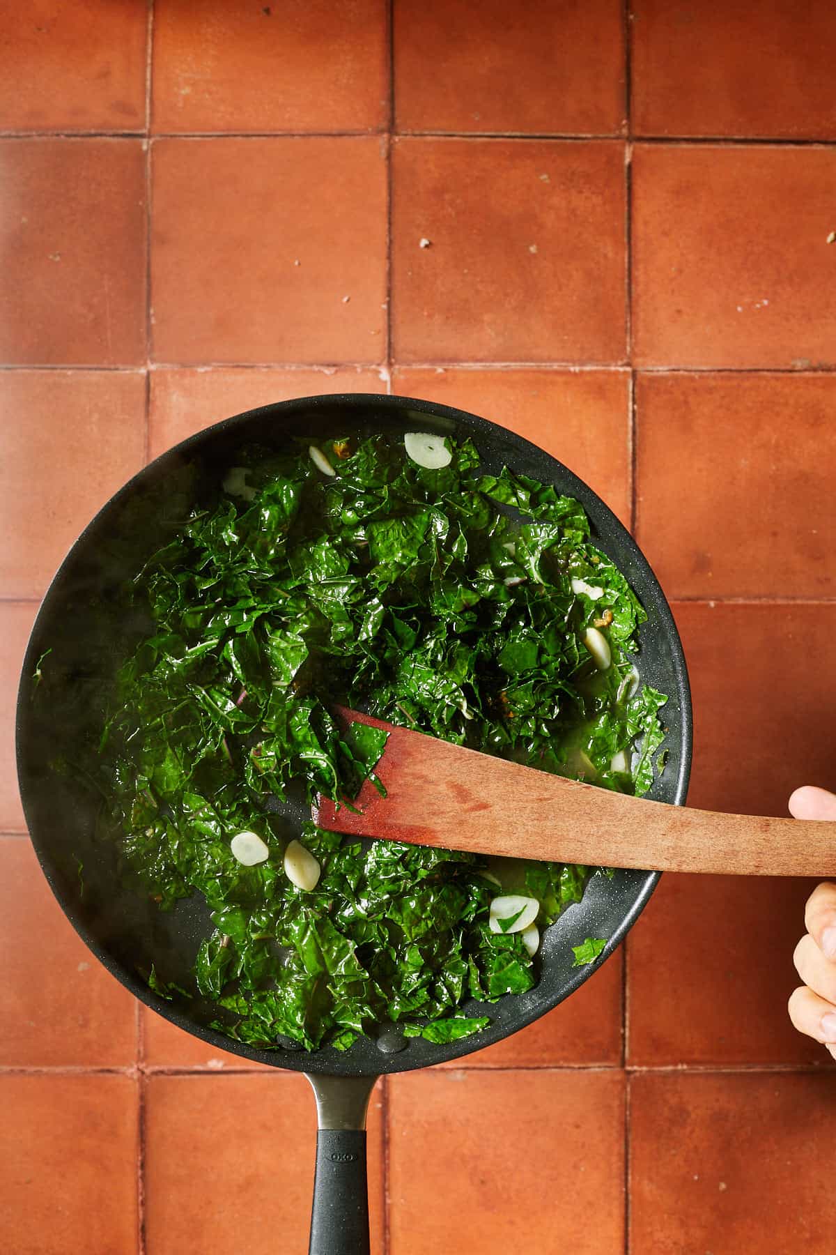 kale cooking down in the pan with sauce and garlic