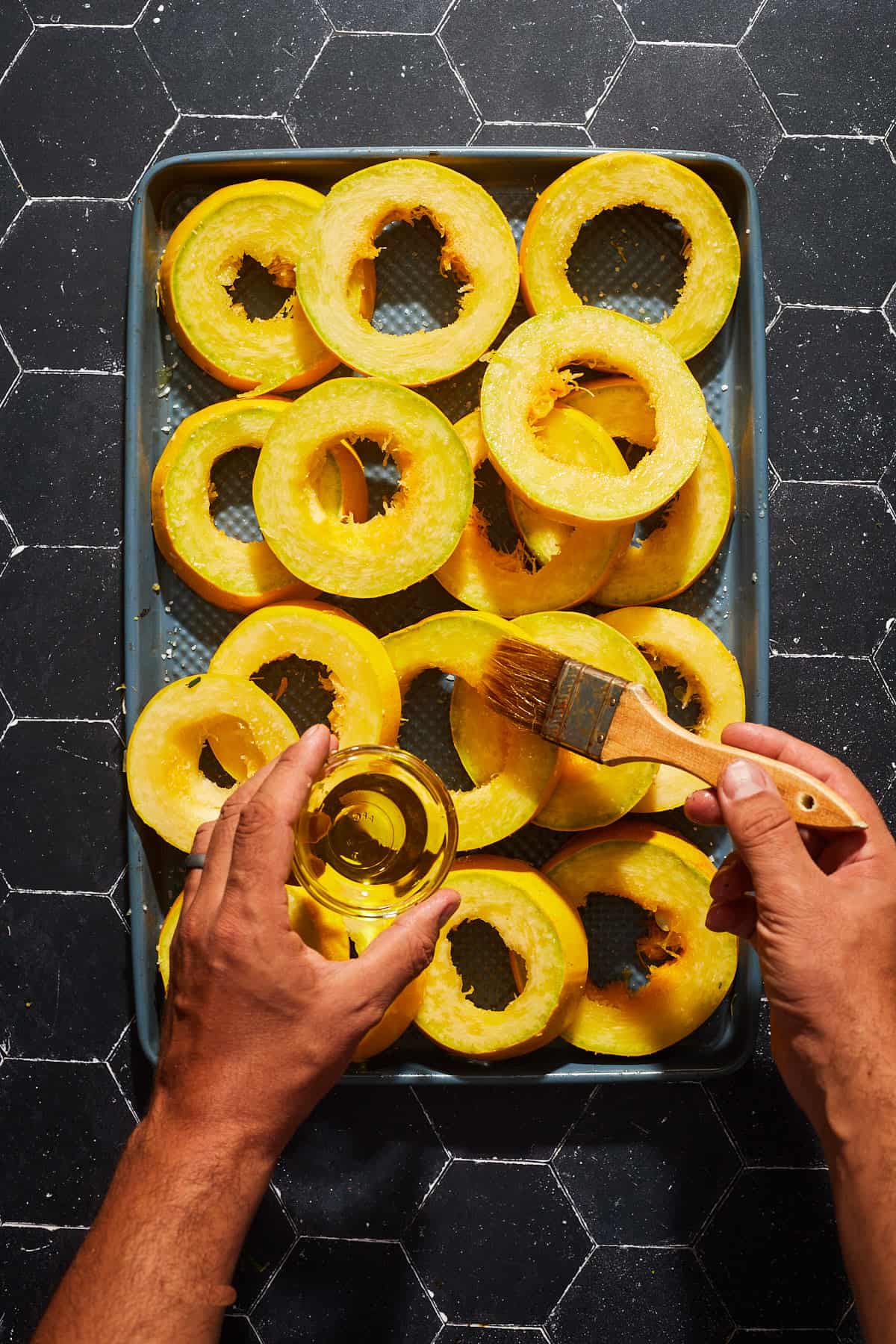sliced spaghetti squash being brushed with olive oil