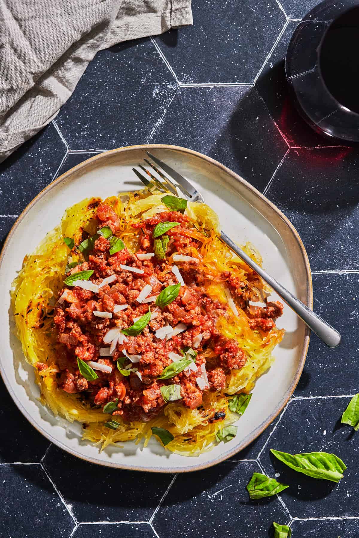 a plate of spaghetti squash topped with meat sauce and basil leaves