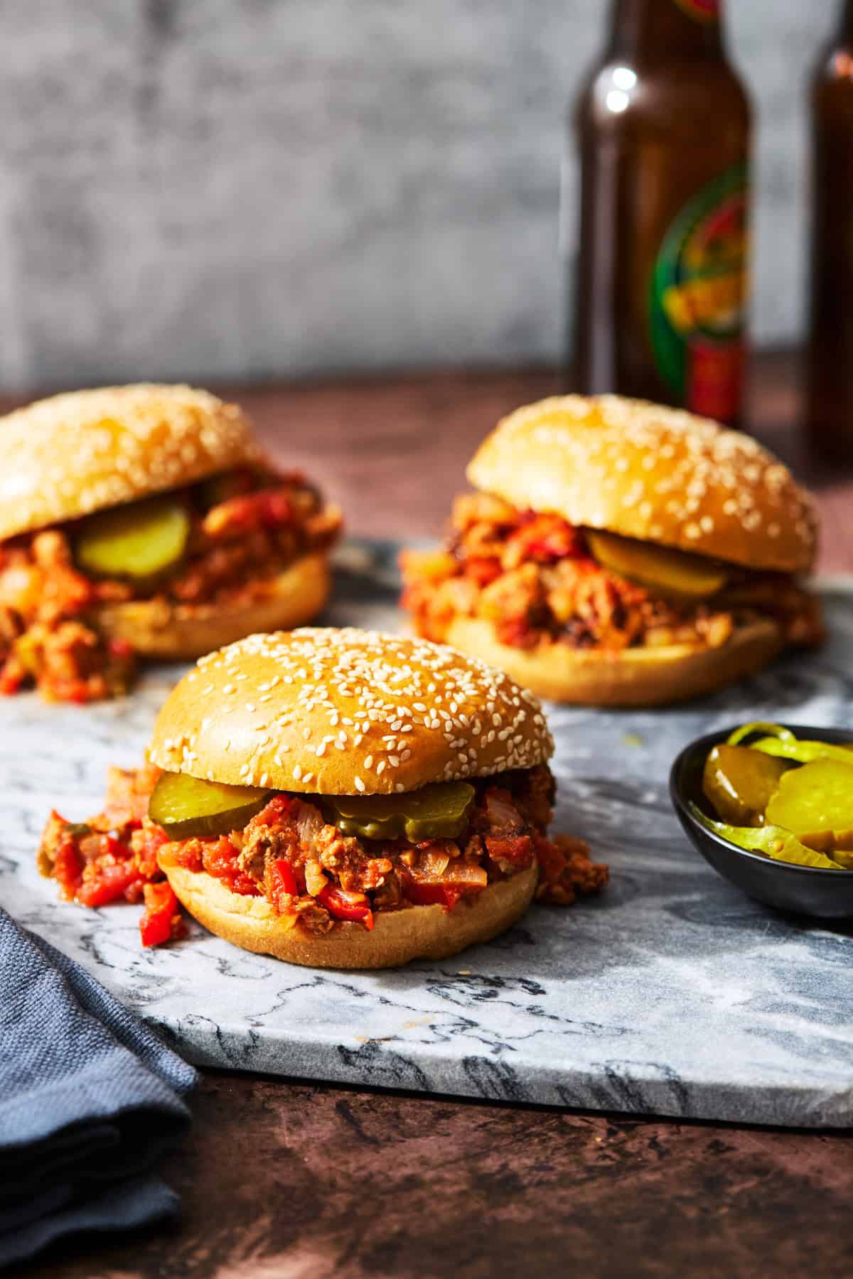 three sloppy joes on a cutting board