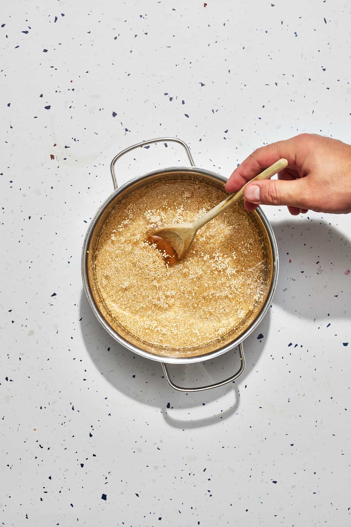 quinoa being stirred in a pot with water
