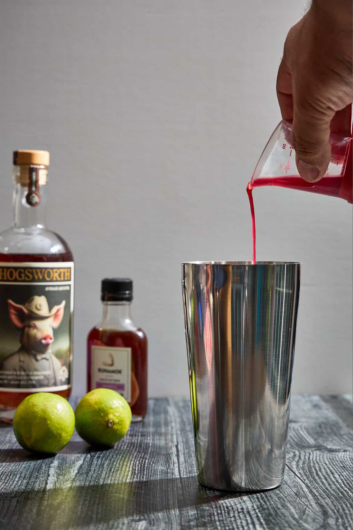 cherry syrup being poured into a cocktail shaker